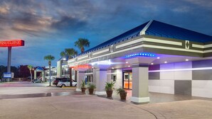 A modern hotel with a covered entrance, palm trees, and a sign reading "TRAVELLOSE".