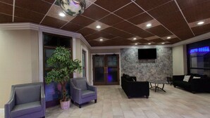 A spacious lobby with a high ceiling, a stone wall, and a large potted plant.