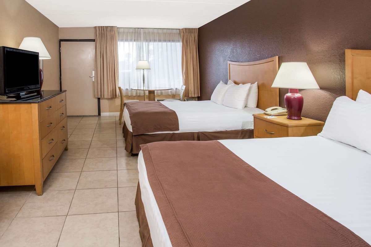 Une chambre d’hôtel avec deux lits, une télévision, un bureau et une chaise.