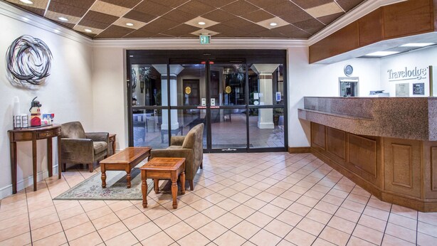 A lobby with a reception desk, seating area, and a large glass door leading to the outside.