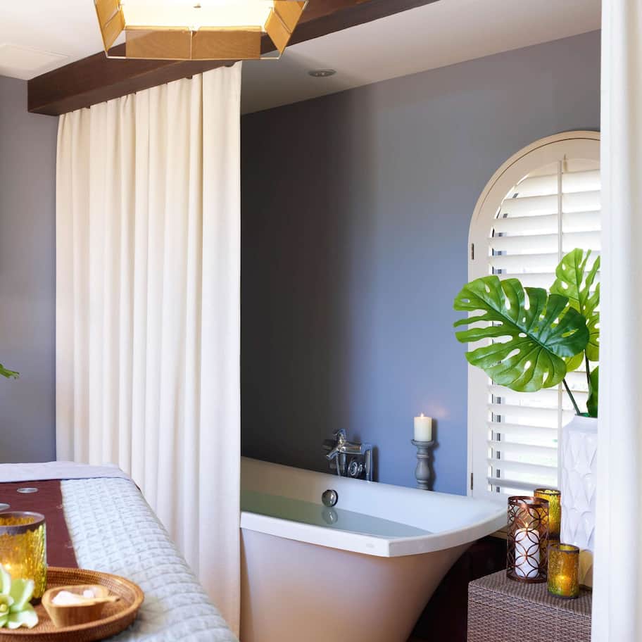 A spa room with a bed, a bathtub, and a vanity area.