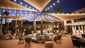 An outdoor seating area with a canopy, lounge chairs, and a fire pit. - San Diego Mission Bay Resort (San Diego)