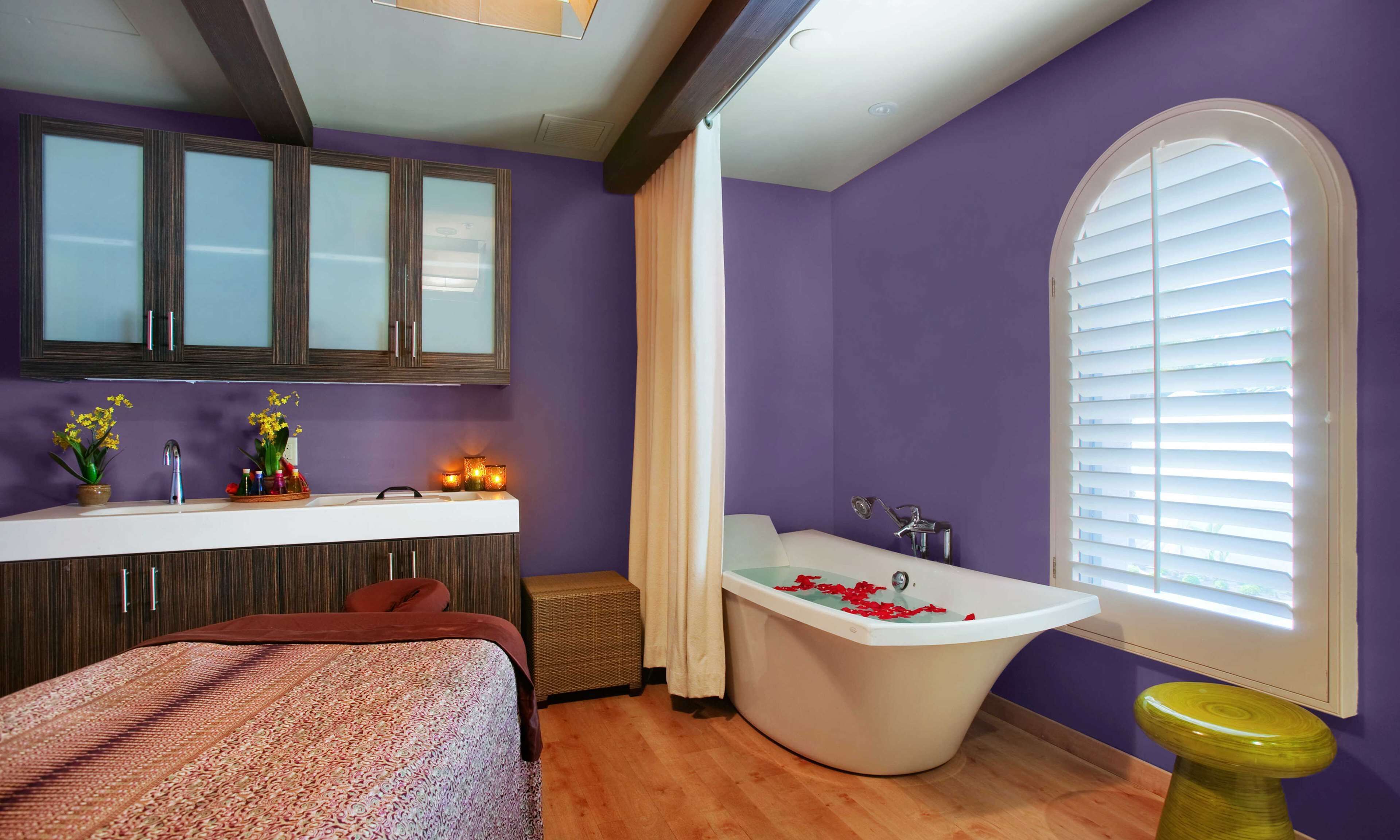 A bathroom with a bathtub, vanity, and a window with blinds.