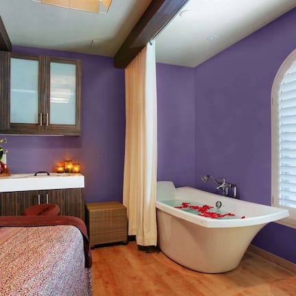 A bathroom with a bathtub, vanity, and a window with blinds.