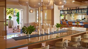 A modern dining area with a glass table, candles, and wicker chairs. - San Diego Mission Bay Resort (San Diego)