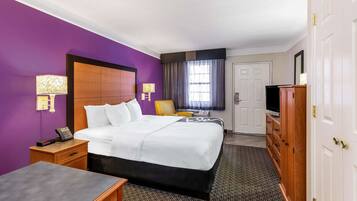 A hotel room with a large bed, a desk, a wardrobe, and a television.