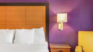 A hotel room with a bed, a nightstand, a lamp, and a yellow armchair.