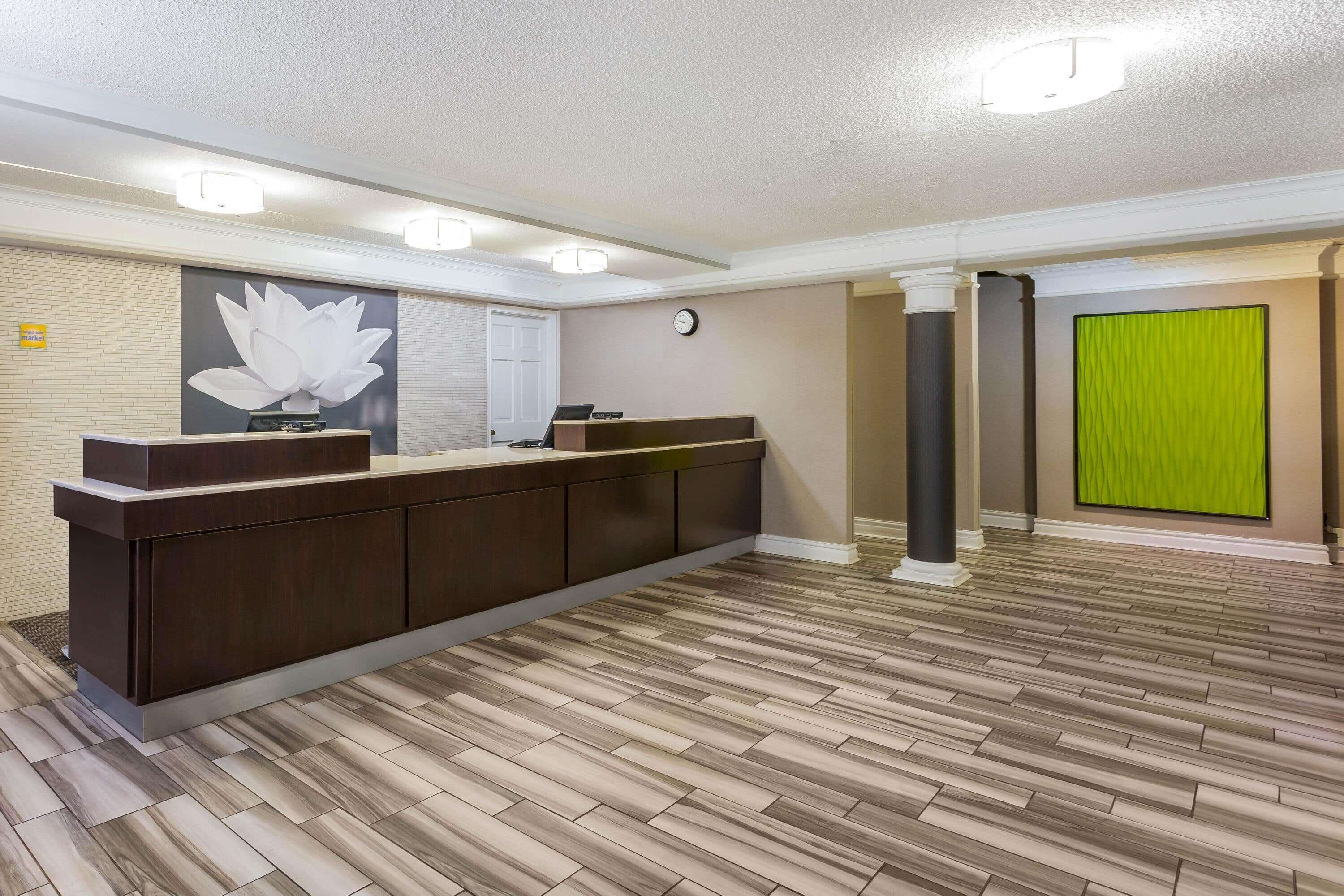 A reception area with a wooden reception desk, a clock on the wall, and a green curtain.