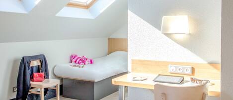 Una habitación moderna con tragaluces, una cama, un escritorio con silla, un televisor y una lámpara.