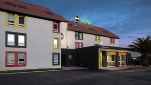 A hotel with a red-tiled roof, multiple windows, and a sign reading "B&B HOTEL". - B&B HOTEL Perpignan Nord (Perpignan)