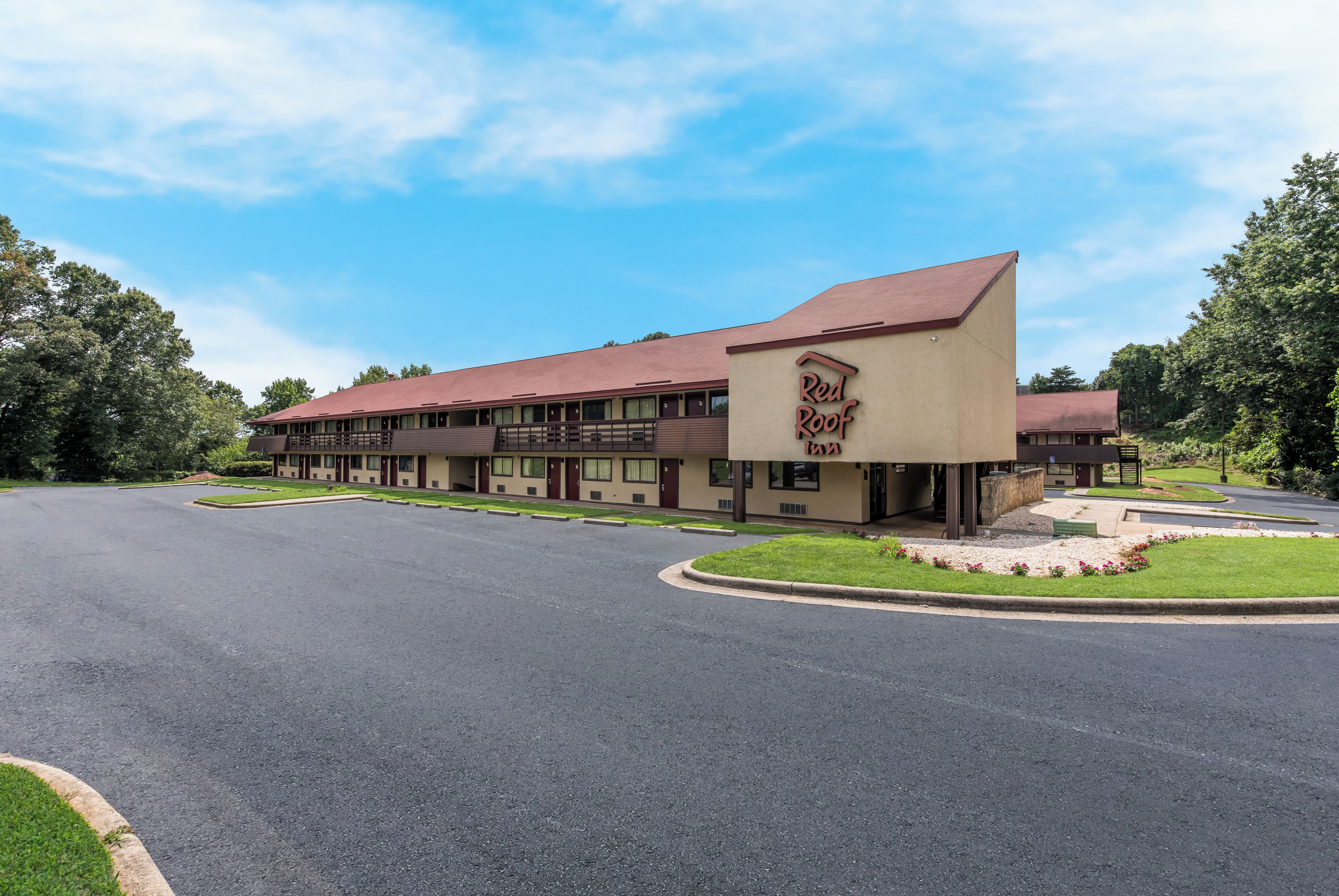 A Red Roof Inn with a red roof, beige exterior, and a parking lot.