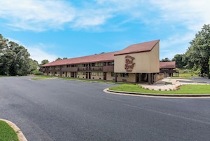Un hotel Red Roof Inn con techo rojo, fachada color beige y estacionamiento.