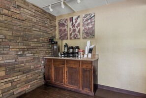 A kitchenette with a stone wall, a coffee machine, and a coffee maker. - Red Roof Inn Hickory (Hickory)