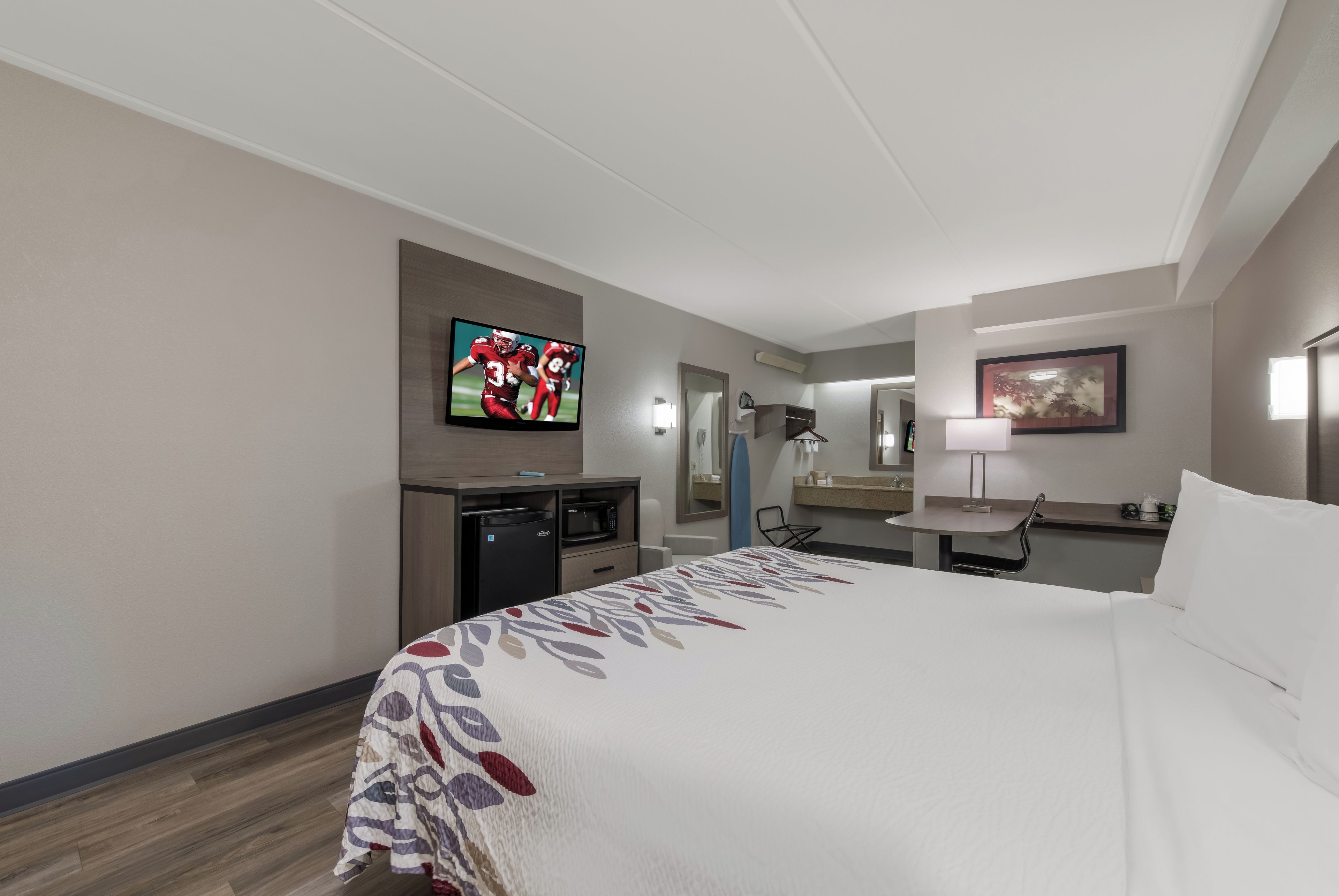 A hotel room with a bed, a desk with a computer, a television, and a bathroom.