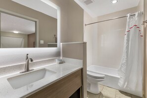 A bathroom with a sink, mirror, toilet, and shower curtain.