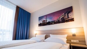 A hotel room with a large bed, two bedside tables, a nightstand, and a painting of a cityscape on the wall. - PLAZA INN Berlin Charlottenburg (Berlin)