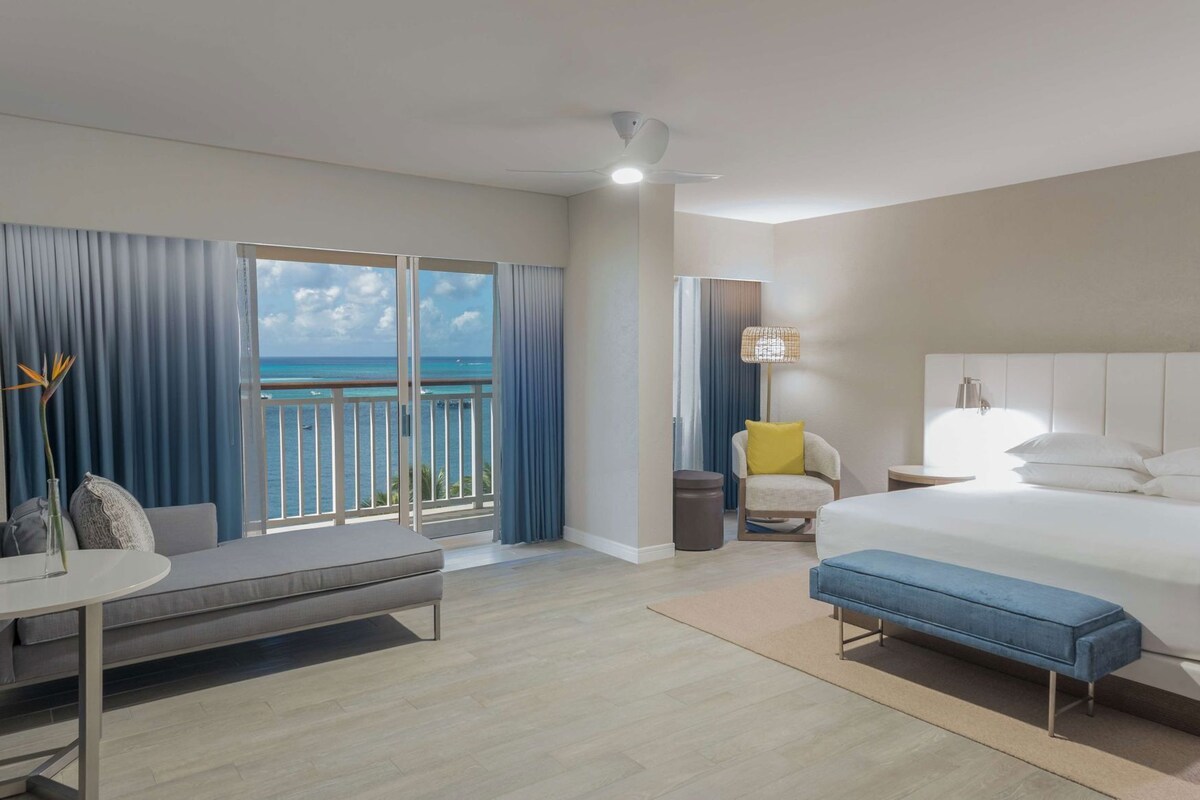 Une chambre d’hôtel avec un balcon, un lit, un canapé, une table et une lampe.