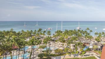 A resort with multiple swimming pools, palm trees, and boats on the water.