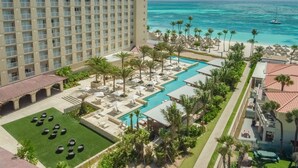 Un hotel con una piscina grande, palmeras y vistas al océano.