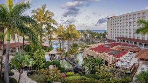 Un resort con piscina, palmeras y un edificio con balcones.