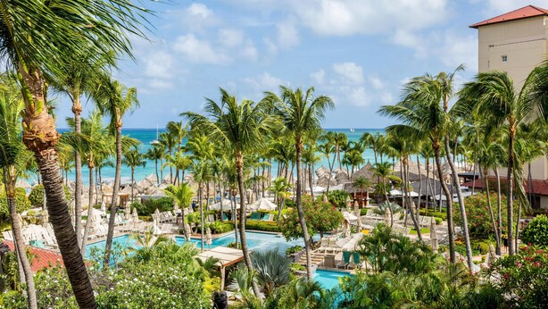 Un resort con piscina, palmeras y vista al océano.