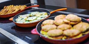 Una cocina con tres ollas en la estufa: una con papas fritas, una con huevos revueltos y una con galletas.