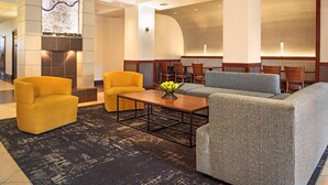 A lobby with a fireplace, seating area, and a wall with a decorative piece. - Hyatt Place Cincinnati/Blue Ash (Cincinnati)