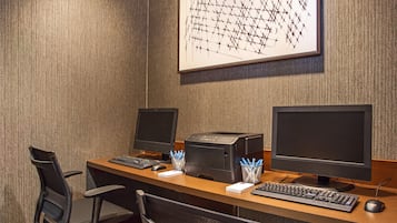 A hotel office with two desks, each equipped with a computer monitor, keyboard, and mouse.