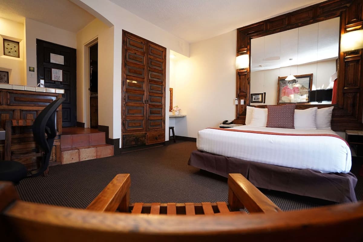 A hotel room with a bed, a desk, a chair, and a staircase.