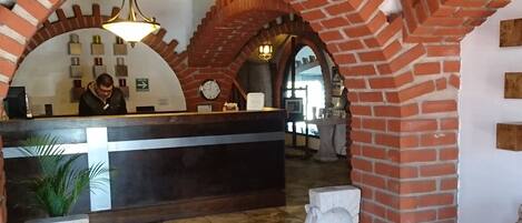 A reception area with a brick archway, a reception desk, and a clock.
