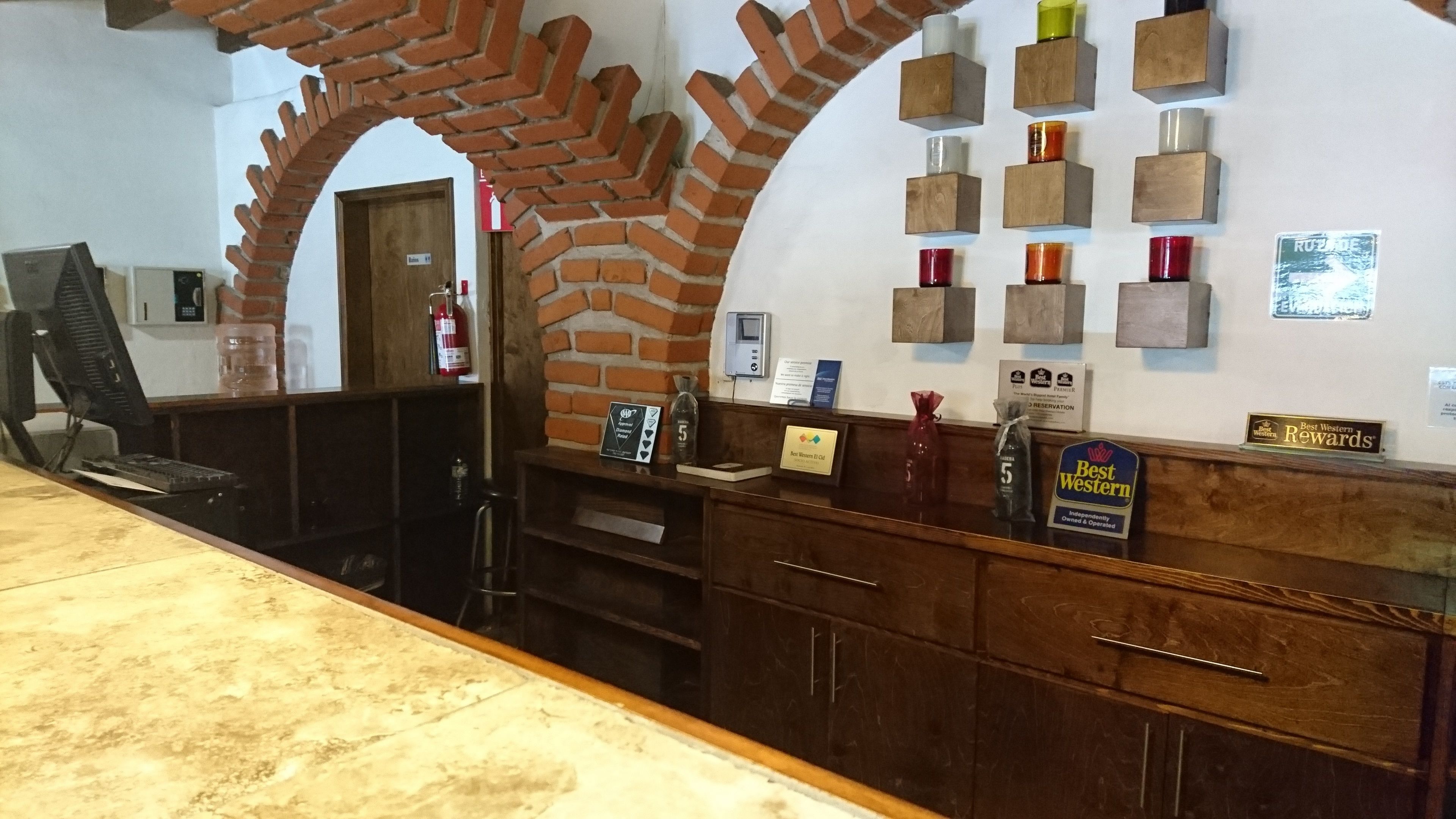 A reception desk with a brick archway, a computer, and various awards and plaques on the wall.