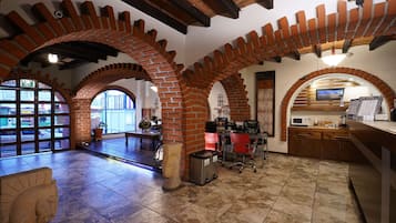 Un interior espacioso con arcos de ladrillo, suelo de baldosas y una zona de cocina con electrodomésticos modernos.