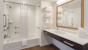 Un baño moderno con bañera, ducha y tocador con espejo.