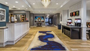 A hotel lobby with a reception desk, a coffee station, and a mural on the wall. - Hampton Inn & Suites Newport/Cincinnati (Newport)