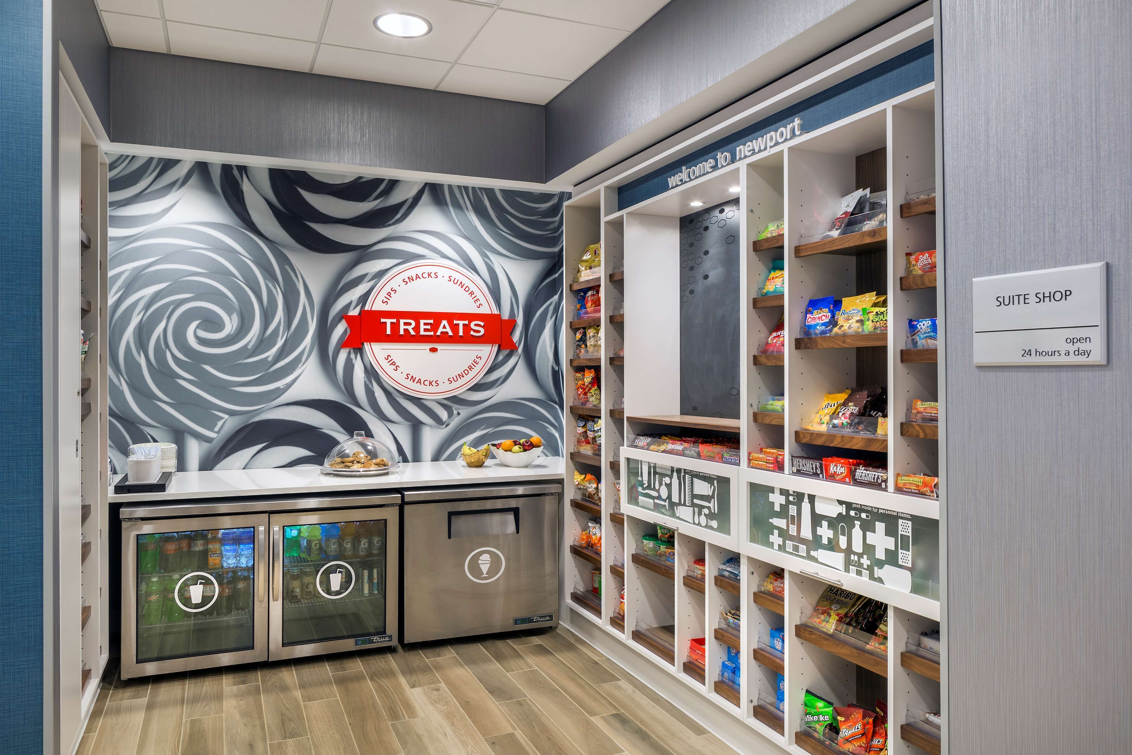 A kitchenette area with a 'TREATS' sign, a 'SUITE SHOP' sign, and shelves stocked with snacks and beverages.