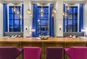 A conference room with a wooden table, purple chairs, and blue curtains.