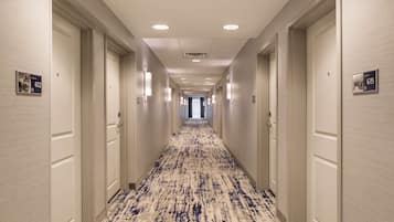 A hotel hallway with a patterned carpet, white walls, and doors numbered 612 and 615.