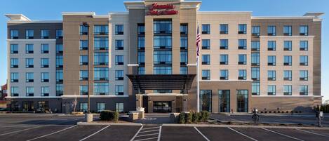 A large, modern hotel with a prominent entrance and a parking lot in front.