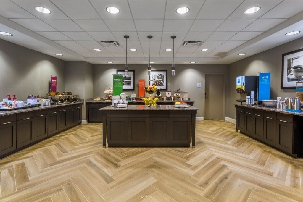 A modern kitchen area with a central island, dark cabinetry, and a herringbone wood floor.