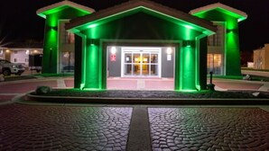 Un edifici amb una entrada il·luminada de verd i un camí de pedra que hi convergeix.