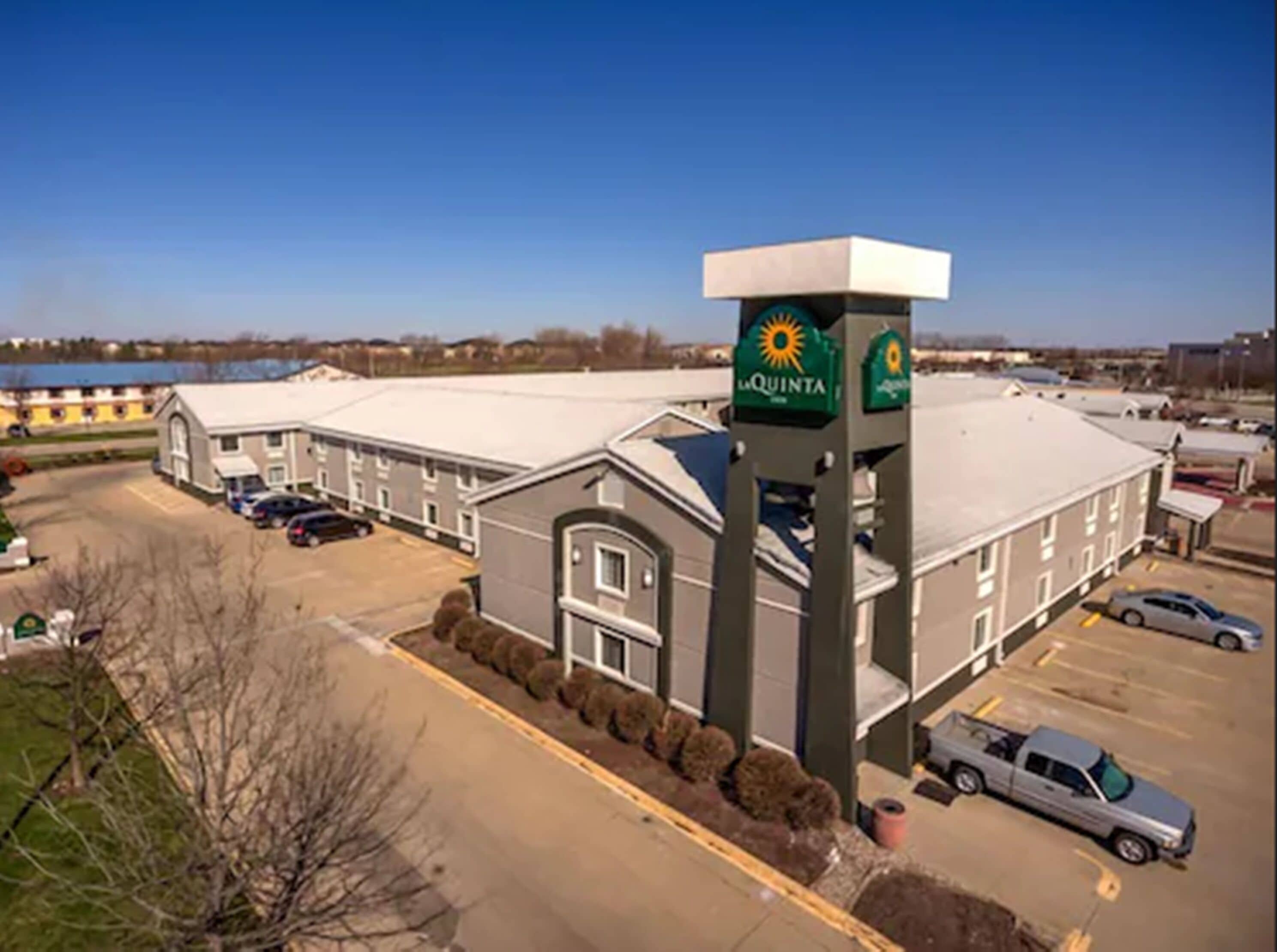 A hotel with a large parking lot, a prominent sign for La Quinta, and a view of a body of water in the background.