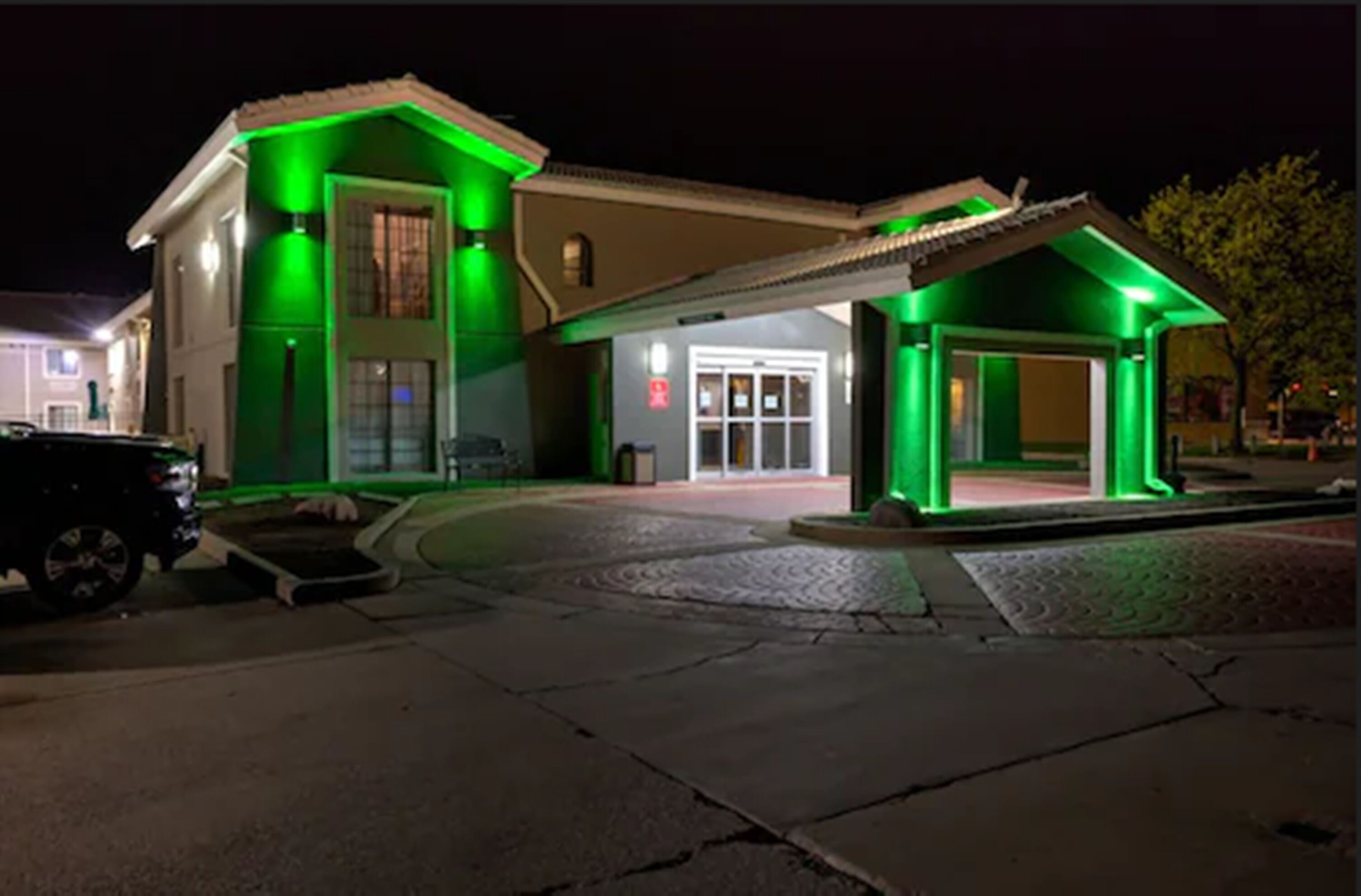 A building with a covered entrance and a car parked in front.