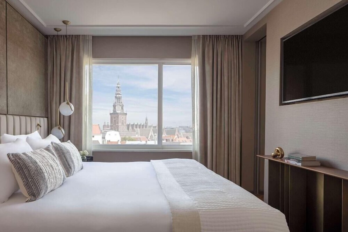 Habitación de hotel con una cama grande, vistas a una torre y un televisor de pantalla plana en la pared.