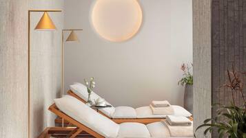 Un cuarto de spa con una mesa de masaje de madera, una lámpara de pared redonda y una planta en maceta.