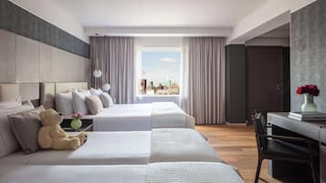 A hotel room with two beds, a desk, and a view of the city.