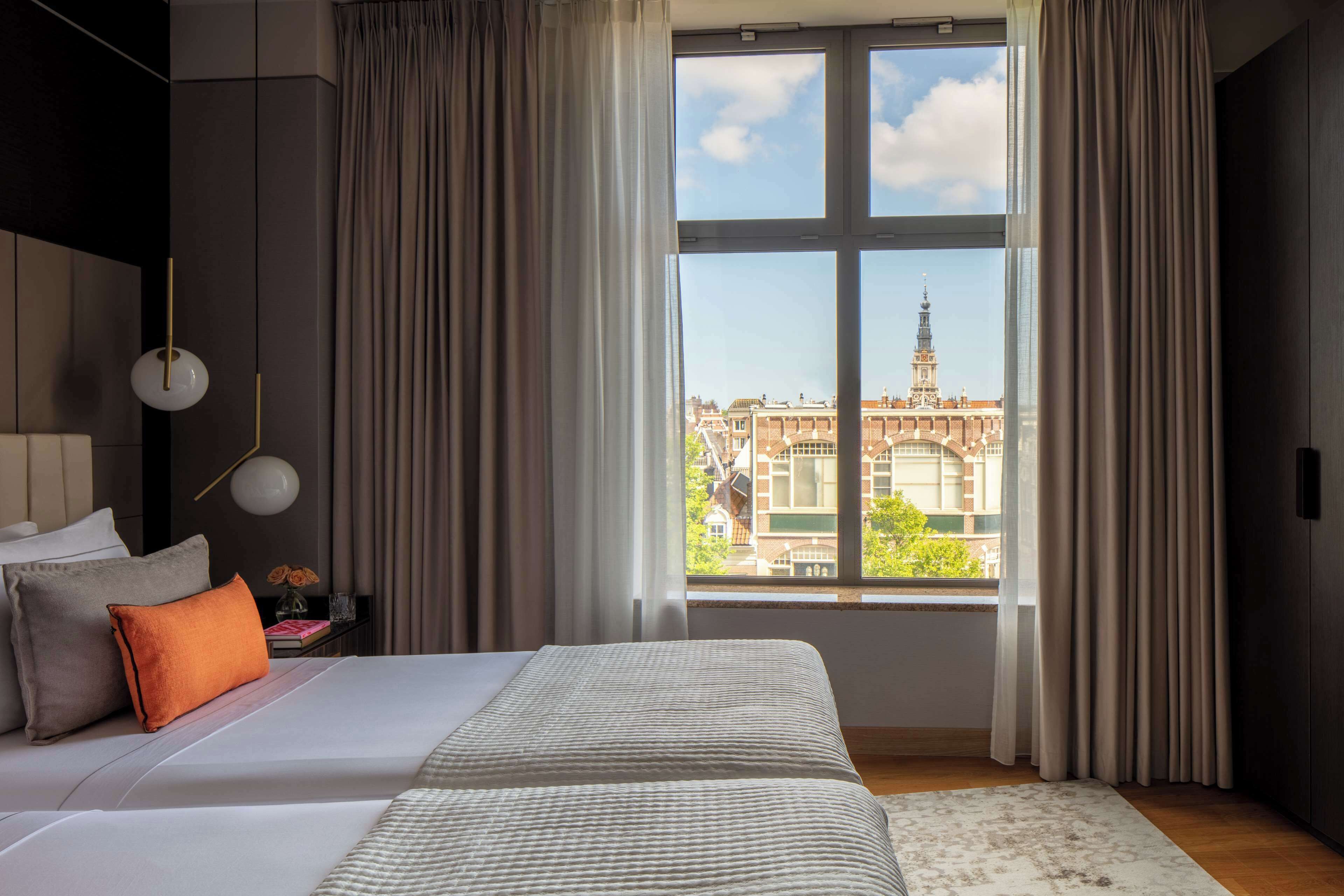 Een moderne hotelkamer met een groot bed, uitzicht op een historisch gebouw en een stadsgezicht.