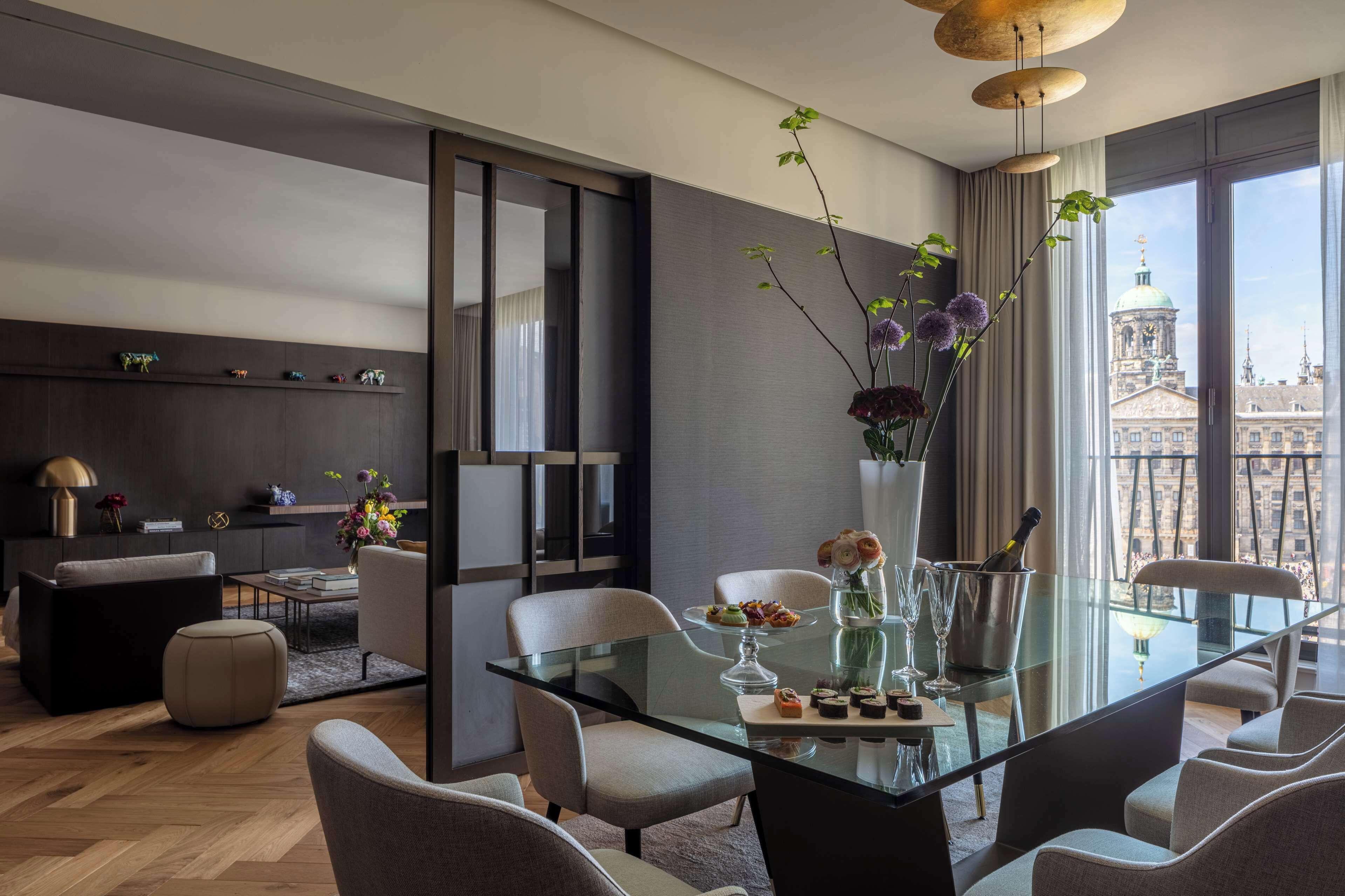 Un comedor moderno con una mesa de vidrio, sillas y un florero con flores.