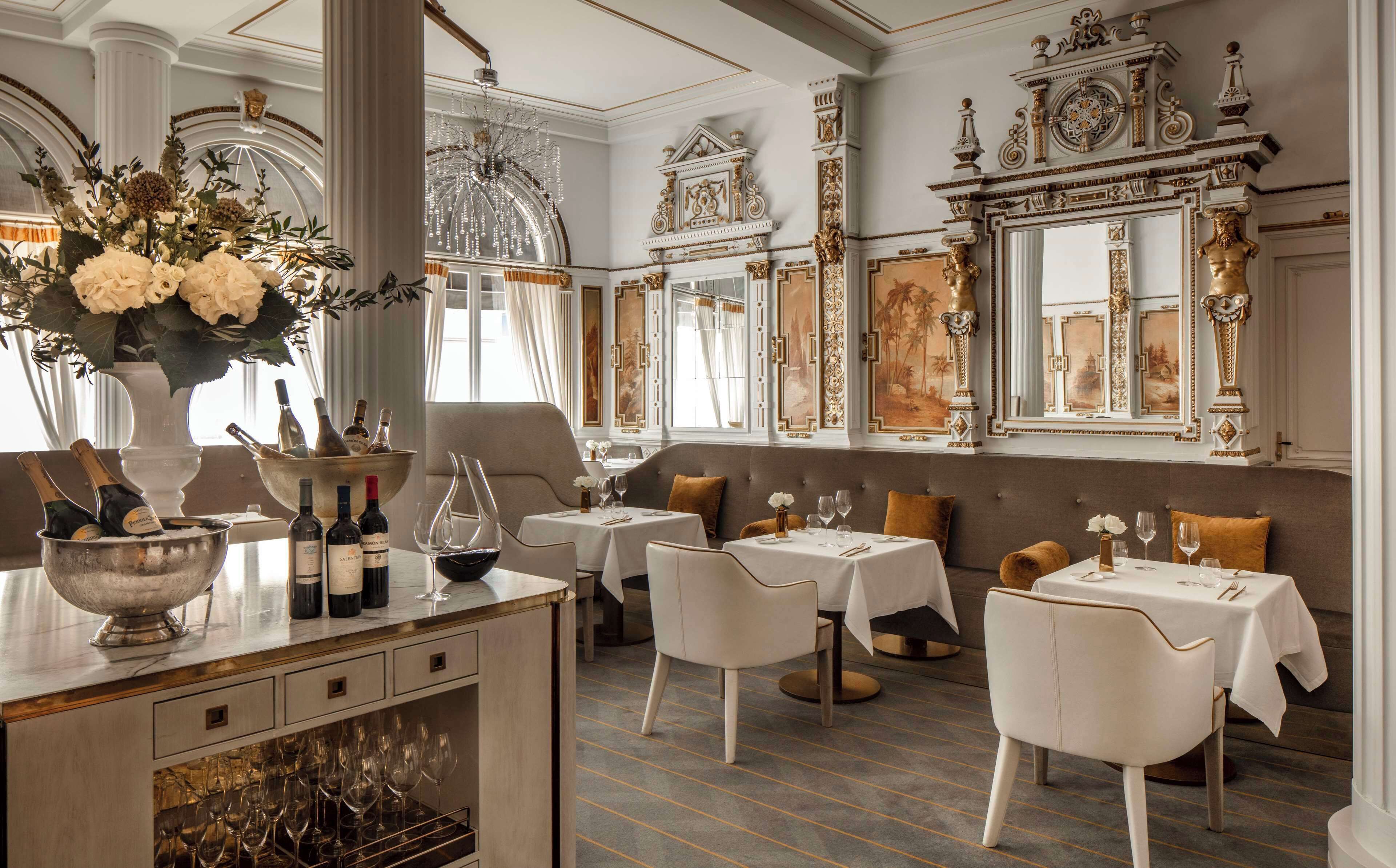 A luxurious dining area with ornate decor, a bar with champagne bottles, and elegant seating.