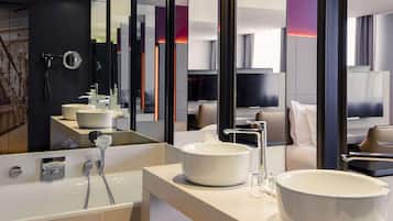 Un baño moderno con una bañera grande, dos lavamanos y un tocador con banco.