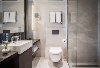 A modern bathroom with a large mirror, a sink, a toilet, and a shower area.